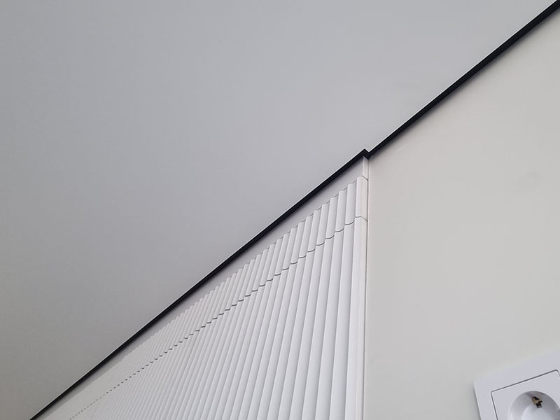 Безупречный стык теневого натяжного потолка с рельефной стеновой 3D-панелью.