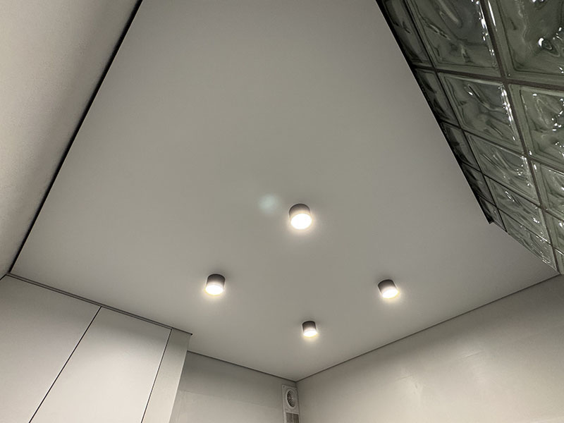 Белый матовый теневой потолок с накладными светильниками в современном интерьере.