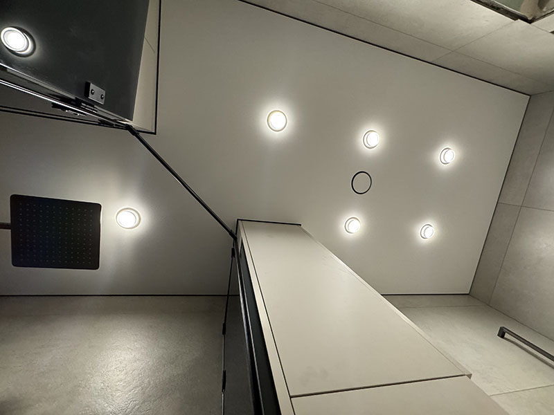 Влагостойкий теневой натяжной потолок со встроенным освещением в интерьере ванной комнаты.