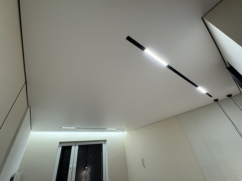 Яркий линейный LED-светильник во встроенном шинопроводе на натяжном потолке